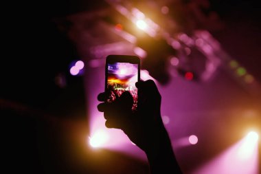 Fotoğraf çekmek ve konser müzik etkinliğinde video kaydetmek için akıllı telefonun soyut renkli arkaplanı, siyah siluet