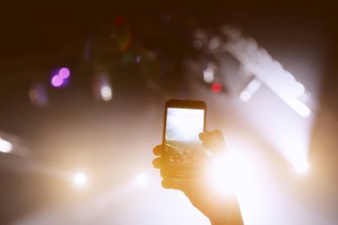 Fotoğraf çekmek ve konser müzik etkinliğinde video kaydetmek için akıllı telefonun soyut renkli arkaplanı, siyah siluet