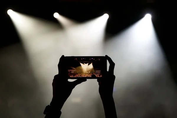 Silhouette of smartphone in the hands of women on the concert show