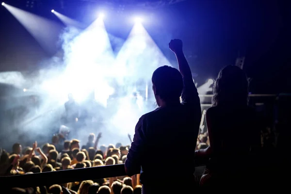 Happy people enjoying rock concert, raised up hands and clapping of pleasure, active night life concept.