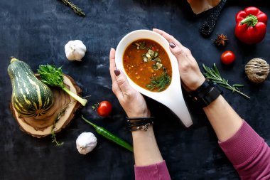 Kız elinde tohumlu sebze çorbasıyla beyaz bir tabak tutuyor.