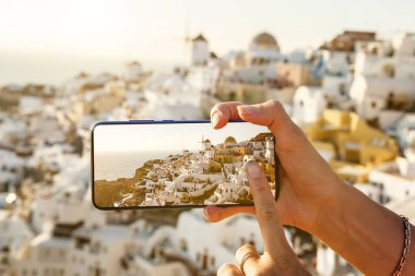 Cep telefonuyla turistik fotoğraflar çekmek. Yunanistan 'ın Santorini adasında akıllı telefon kullanımı