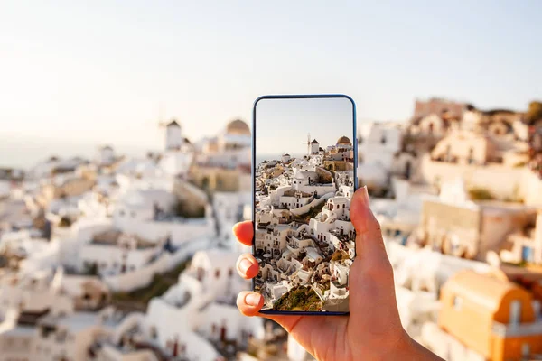 携帯電話のカメラでランドマークを撮影する スマートフォンの画面上でギリシャのサントリーニ島の有名な景色 — ストック写真