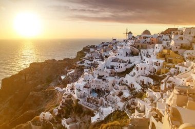 Santorini 'nin ünlü manzarası beyaz evler ve gün batımında yel değirmeni. Yunanistan 'da Ege Denizi' nde Tatil