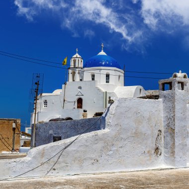 Yunanistan 'daki Santorini adasında mavi kubbeli beyaz bir kilise. Sıcak yaz güneşi günü