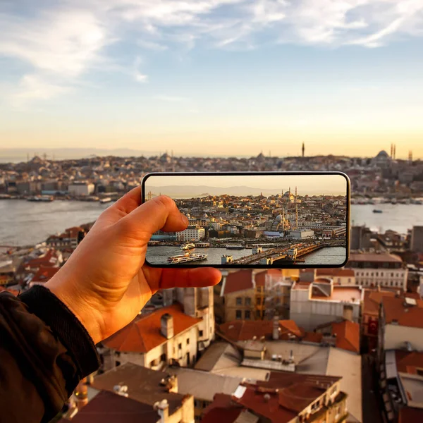 Taking photos and video of sunset Istanbul landscape via smartphone. Tourist with mobile phone in Turkey