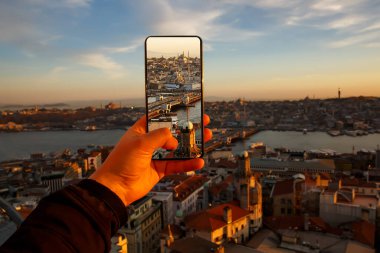 Akıllı telefondan günbatımının fotoğraflarını ve videosunu çekiyor. Türkiye 'de cep telefonu olan bir turist