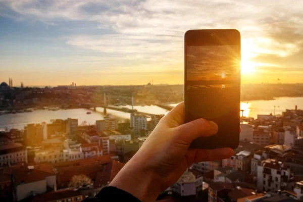 Taking photos and video of sunset Istanbul landscape via smartphone. Tourist with mobile phone in Turkey