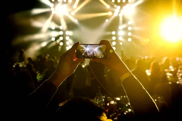 The fan holding his smart mobile phone and photographing a rock concert