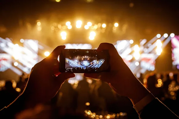 The fan holding his smart mobile phone and photographing a rock concert