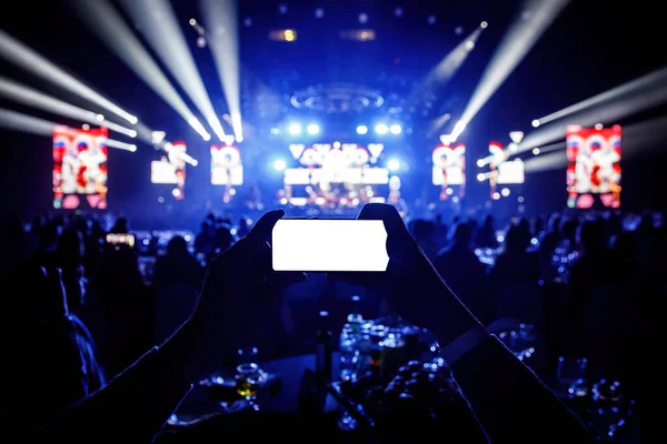 Smartphone in a hands on a music concert show, blank white screen mockup