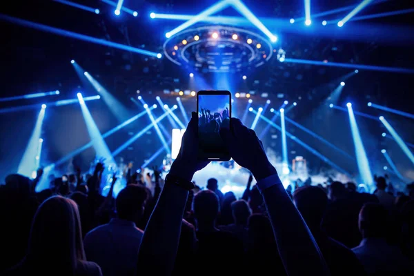 The fan holding his smart mobile phone and photographing a rock concert