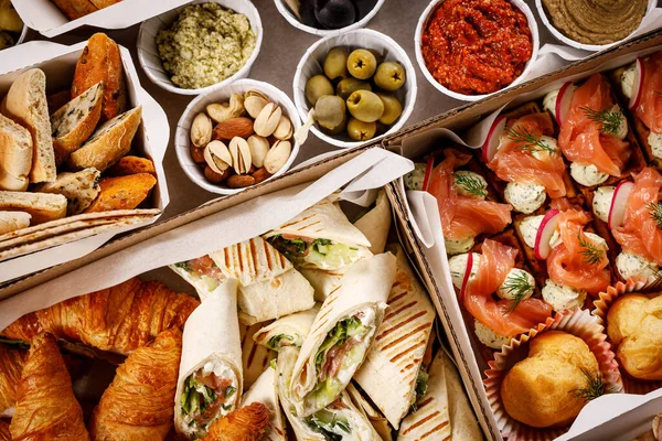 Mukavva bir kutuda çeşitli atıştırmalıklar. Sandviç, sebze, sos ve kanepe.