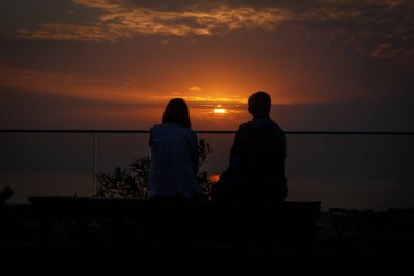 İki insan, erkek ve kadın, gün batımına bakın.