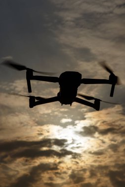 Gökyüzündeki dramatik bulutlara karşı bir dronun silueti