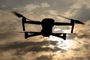 Gökyüzündeki dramatik bulutlara karşı bir dronun silueti