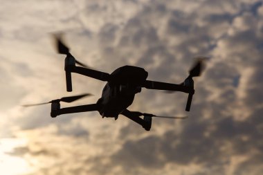 Gökyüzündeki dramatik bulutlara karşı bir dronun silueti
