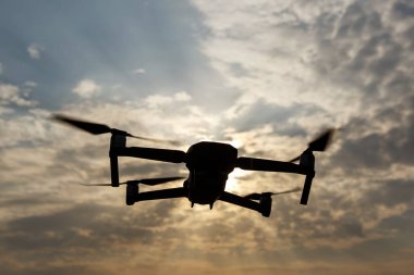 Gökyüzündeki dramatik bulutlara karşı bir dronun silueti