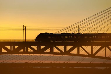 Nehrin üzerindeki demiryolu köprüsünde trafik vardı. Gün batımında tren