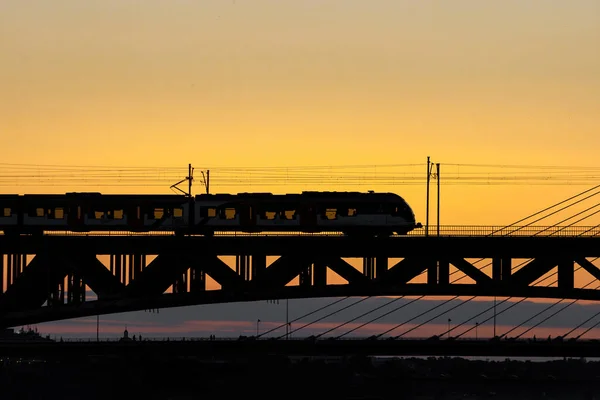 Der Zug Fährt Bei Sonnenuntergang Über Die Brücke Über Den — Stockfoto