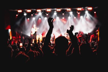 Müzik konserinde elini kaldırmış bir adamın silueti..