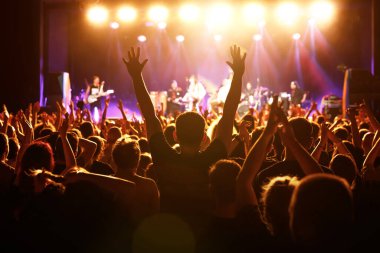 Müzik konserinde elini kaldırmış bir adamın silueti..