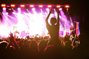 Müzik konserinde elini kaldırmış bir kız silueti..