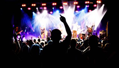 Silhouette of a young man on a concert with raised hand, big festival event