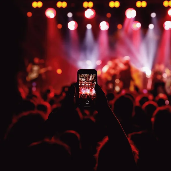 Holding a smartphone to record music concert. Mobile phone at a summer festival