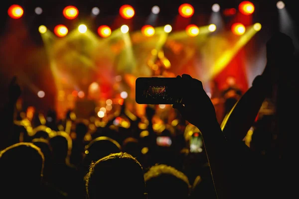 Holding a smartphone to record music concert. Mobile phone at a summer festival