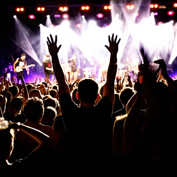 Silhouette of a young man on a concert with raised hand, big festival event