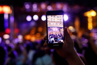 People holding their smartphones at concert and taking pictures