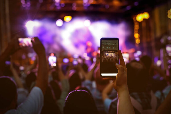 People holding their smartphones at concert and taking pictures