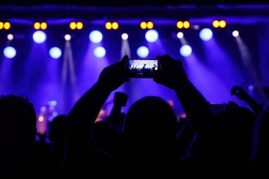 Holding a smartphone to record music concert. Mobile phone at a summer festival