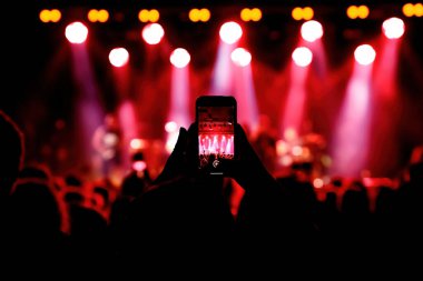 Holding a smartphone to record music concert. Mobile phone at a summer festival