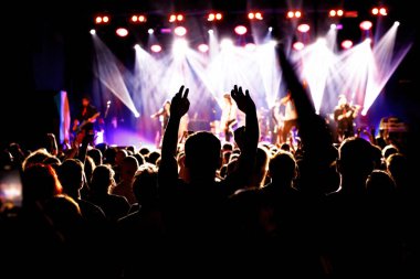 Silhouette of a young man on a concert with raised hand, big festival event