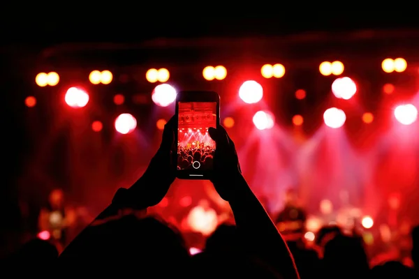 Holding a smartphone to record music concert. Mobile phone at a summer festival