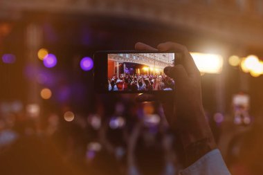 People holding their smartphones at concert and taking pictures