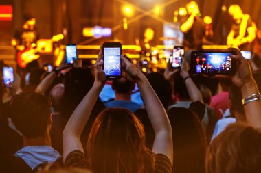 People holding their smartphones at concert and taking pictures