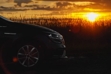 Gün batımında arabanın önünde. Yan manzara.