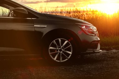 Gün batımında arabanın önünde. Yan manzara.