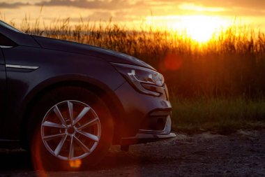 Günbatımında modern bir arabanın farları