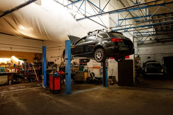 Car raised on car lift at auto repair service.