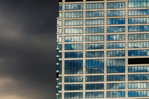 Mirrored office building windows with dramatic clouds background