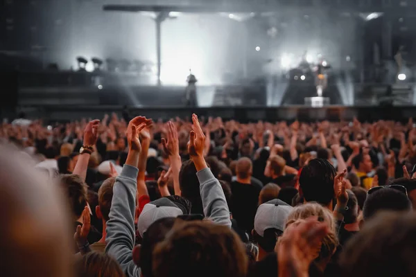 Performance of a popular group. The crowd with raised hands against the stage light