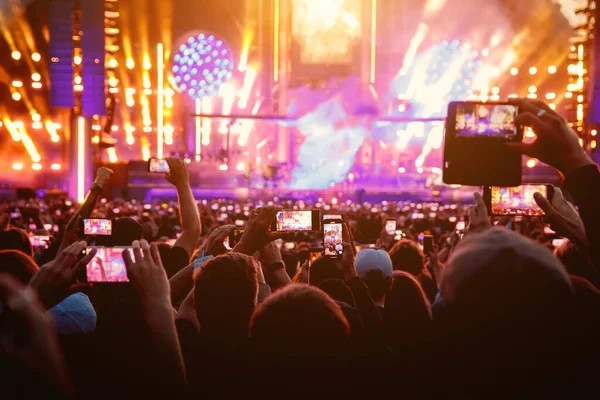 People raised their mobile phones to record live concert. People smartphones on the music show festival
