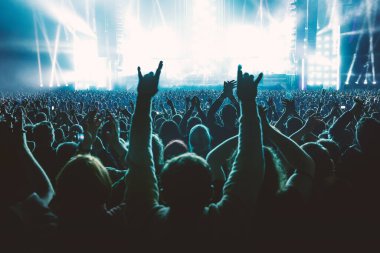 A lot of people raised up hands at the concert event. Fans arms against the stage light