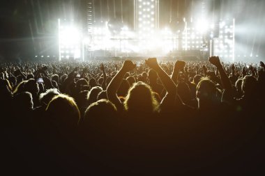 People with raised hands at a music concert. Fans in a concert hall
