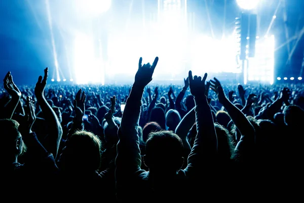 People with raised hands at a music concert. Fans in a concert hall