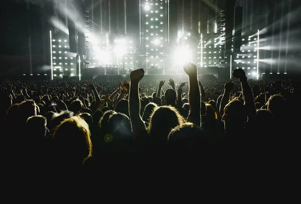 People with raised hands at a music concert. Fans in a concert hall